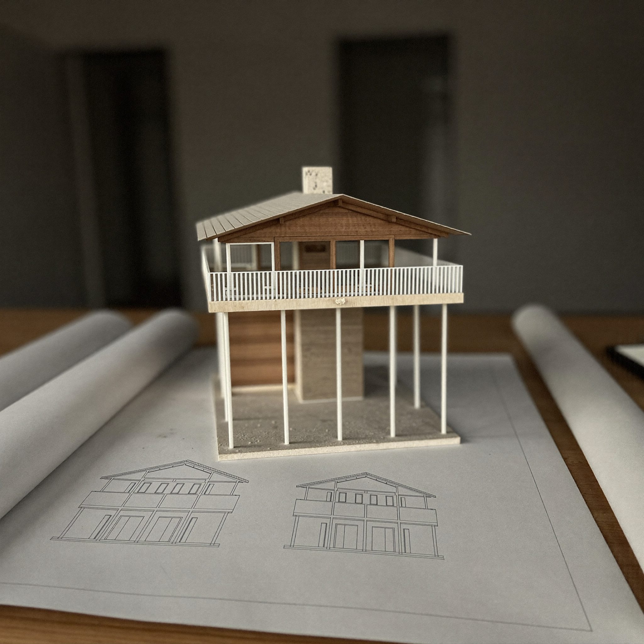 Maket arsitektur dan denah di atas meja kerja